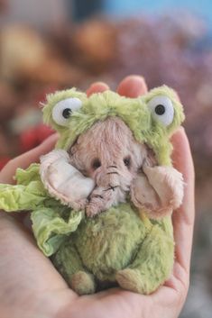 a hand holding a small stuffed animal with eyes on it's face and mouth