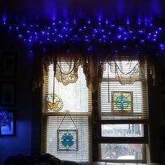 a window with blue lights hanging from it's side and curtains on the other side