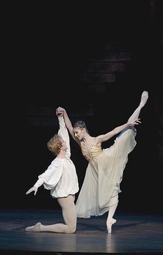 two ballerinas are performing on stage with one holding the other's leg