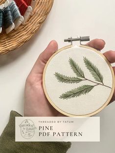 a person is holding a cross - stitched pine leaf in front of a basket