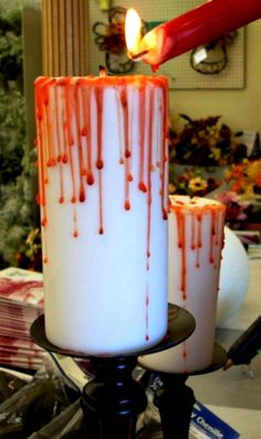 two candles with blood running down them on a table