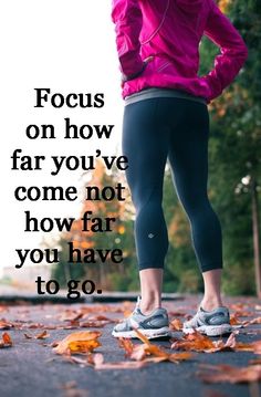 a woman in pink jacket and black leggings standing on street with text focus on how far you've come not how far you have to go