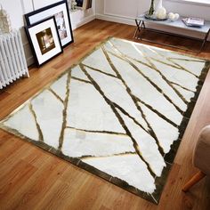 a white and gold rug in the middle of a living room with wood flooring