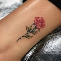 a small rose tattoo on the right side of the leg, with leaves around it