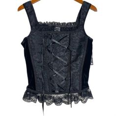 a black corset is hanging on a wooden hanger and it has lace