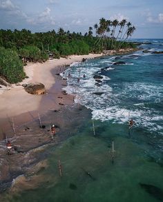 an aerial view of the beach and ocean with people on surfboards in the water