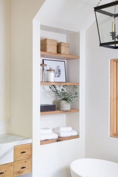 a white bath tub sitting next to a wooden shelf