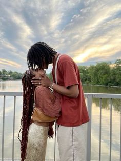 two people standing next to each other near water