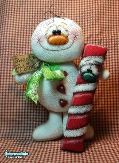 a snowman holding a candy cane on top of a red and white checkered blanket