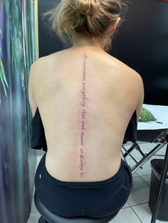 the back of a woman's upper body with writing on her left arm and lower back