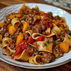 a white plate topped with pasta and meat covered in sauce on top of a wooden table