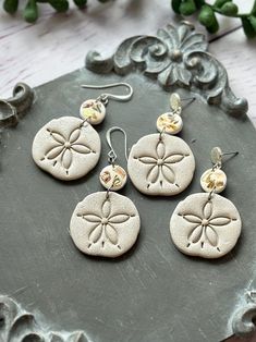 four sand dollar earrings are sitting on a table