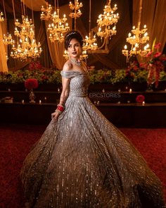 a woman in a dress standing next to a chandelier