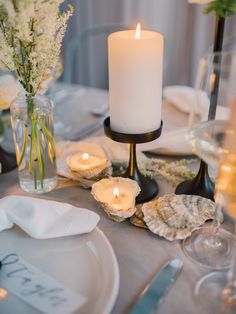 a table set with candles, plates and silverware