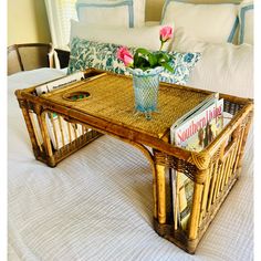 a wicker coffee table with magazines and flowers in a glass vase on the top