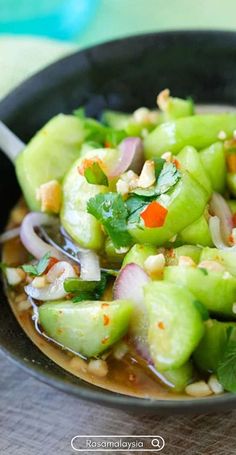 a black bowl filled with cucumber and onions