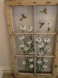 an old window with flowers in it and hummings on the glass pane above