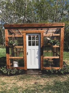 a small wooden structure sitting on top of a grass covered field next to a white door