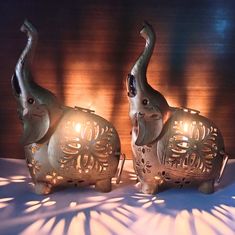 two elephant figurines sitting next to each other on top of a white table