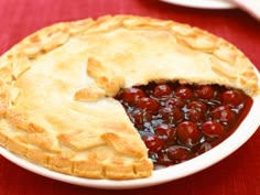 a cherry pie on a plate with one slice cut out