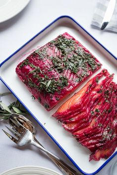 two slices of fish on a plate with herbs