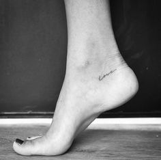 a woman's foot with the word love written on it and a small tattoo