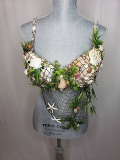 a mannequin is adorned with seashells and plants