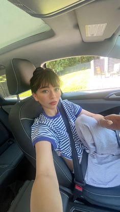 a woman sitting in the back seat of a car with her hand on the steering wheel