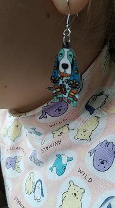 a close up of a person wearing earrings with animals on them