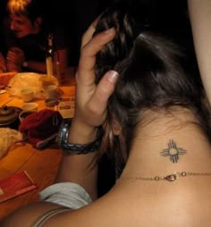 a woman with a tattoo on her neck is sitting at a table in front of other people