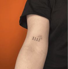 a person with a small tattoo on their arm that reads 11 11 and has the number 11 in it