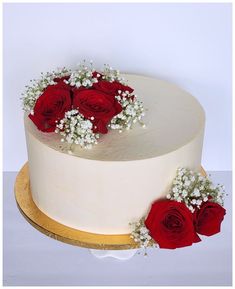 a white cake topped with red roses and baby's breath