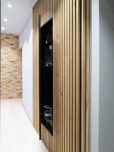 an empty room with wooden slats on the wall and black cabinets in the corner