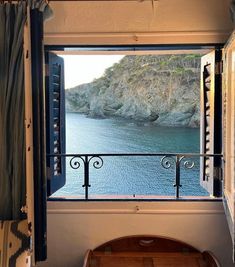 an open window looking out at the ocean and cliffs from a bedroom with a balcony