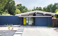 a blue house with a yellow door in the front yard