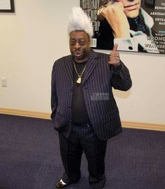 an older man in a suit and white hair standing next to a wall with posters on it