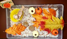 a plastic container filled with fall leaves and acorns on top of rice krispy kreme