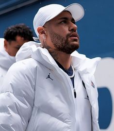 a man in white jacket and hat holding a tennis racket