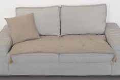 a couch with two pillows on it and one pillow is folded over the other side