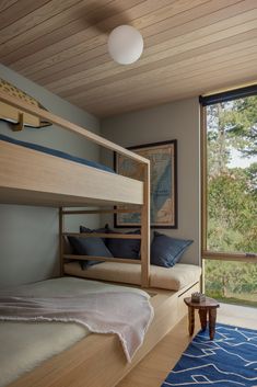 a bunk bed sitting in the middle of a bedroom next to a window with lots of windows