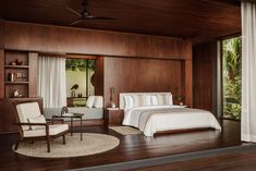 a bedroom with wood paneling and white bedding in front of a large window