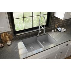 a kitchen sink sitting under a window next to a faucet and counter top