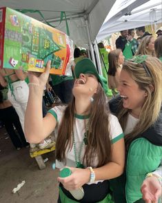 two girls are laughing and looking at a book