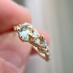 a close up of a person's hand holding a ring with an aqua stone