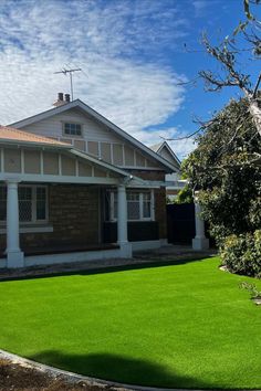 a house with grass in front of it and a tree on the other side of the house