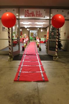 a red carpeted entrance way to a store with large balloons on the floor and decorations