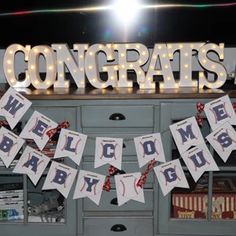 congratulations welcome baby sign and bunting banner in front of an old dresser with lights