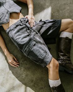 a woman laying on the ground with her legs crossed wearing boots and denim overalls