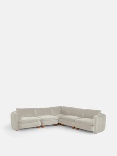 a white sectional couch with two wooden legs and a rounded backrest, facing the camera