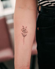 a woman's arm with a small flower tattoo on the left side of her arm